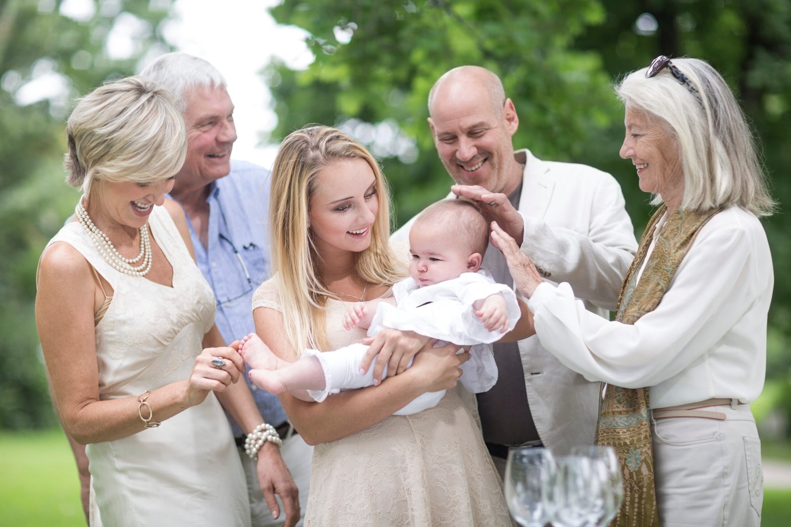 Family gathering around baby outdoors